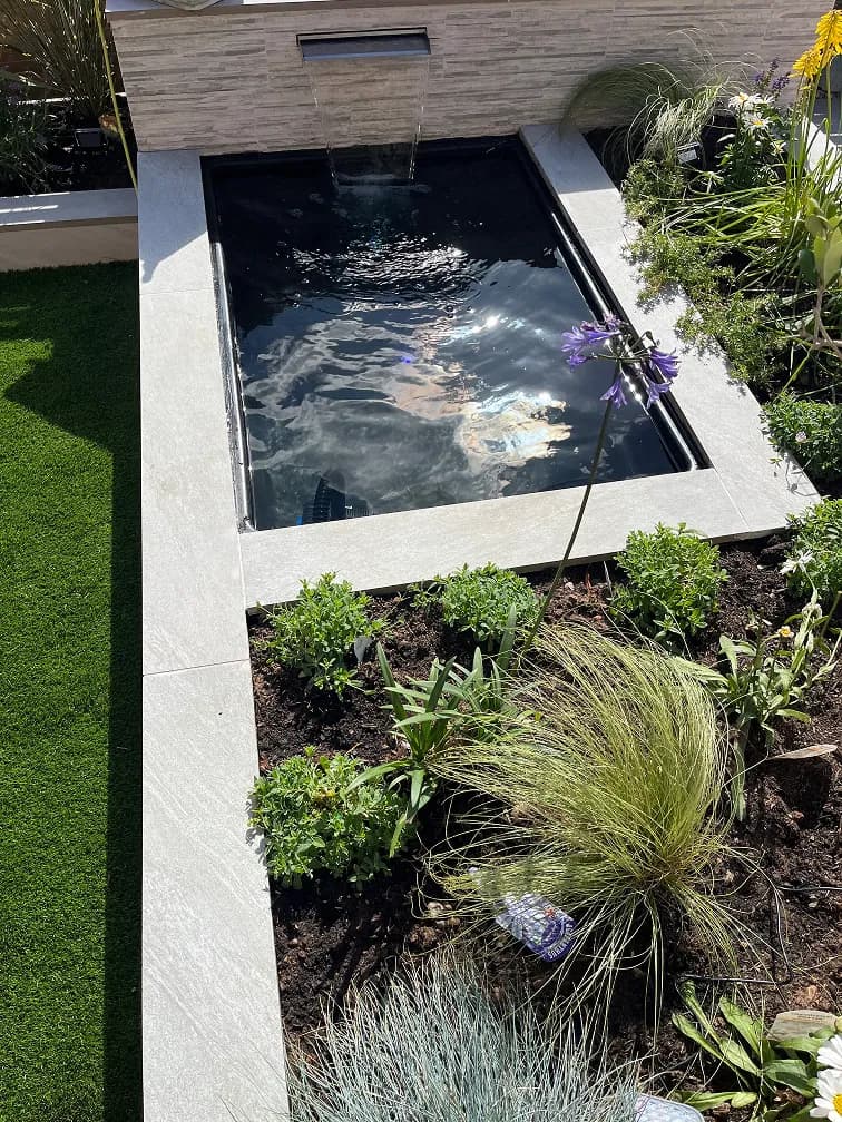 Raised garden pond with water blade feature in a Leicestershire garden.