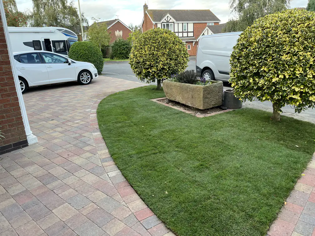 Block paving driveway bordered by a curved lawn and clipped topiary, refreshing this front garden with tidy kerb appeal.