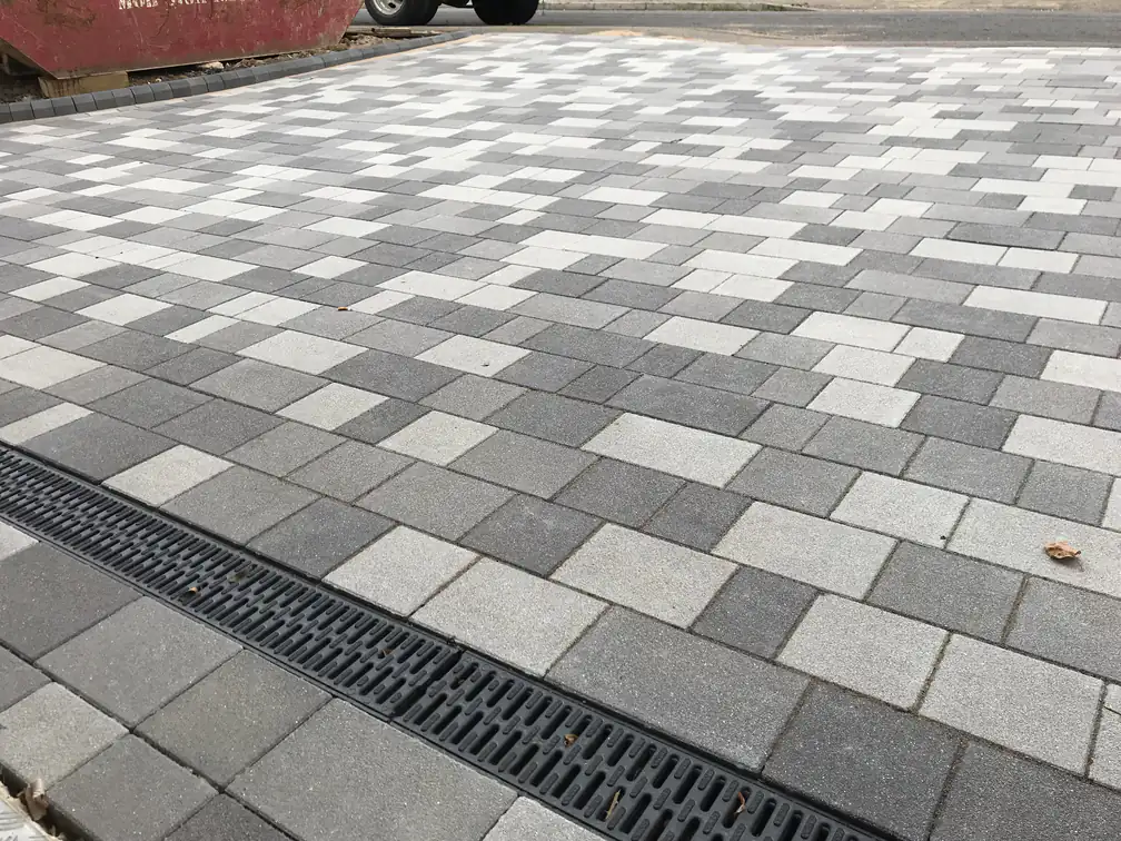 Mixed grey block paving with recessed drainage channel detail, engineered to handle British weather smartly.