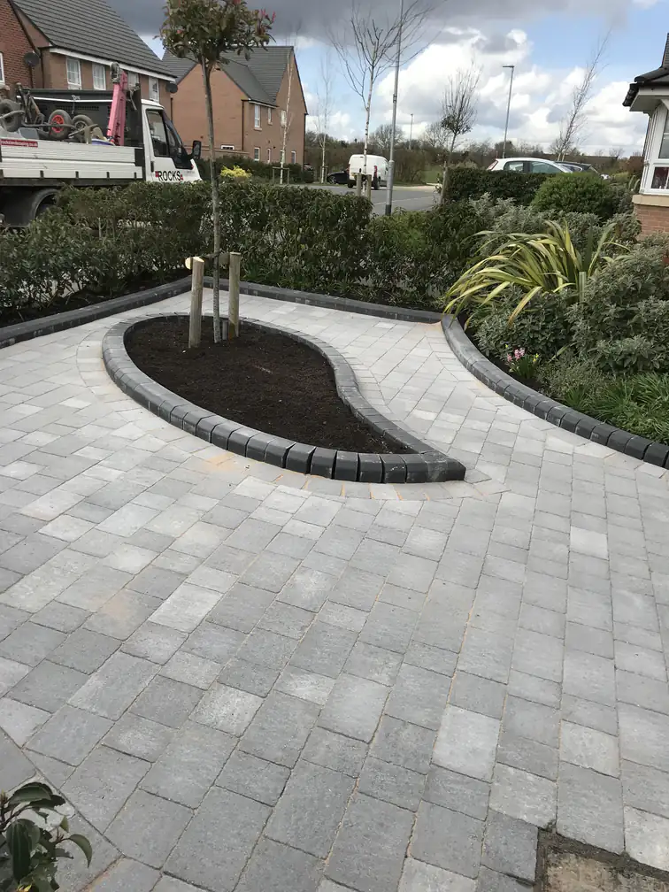 Block paving driveway in silver-grey with contrasting charcoal edging and teardrop island bed, adding kerb appeal to a new-build frontage.