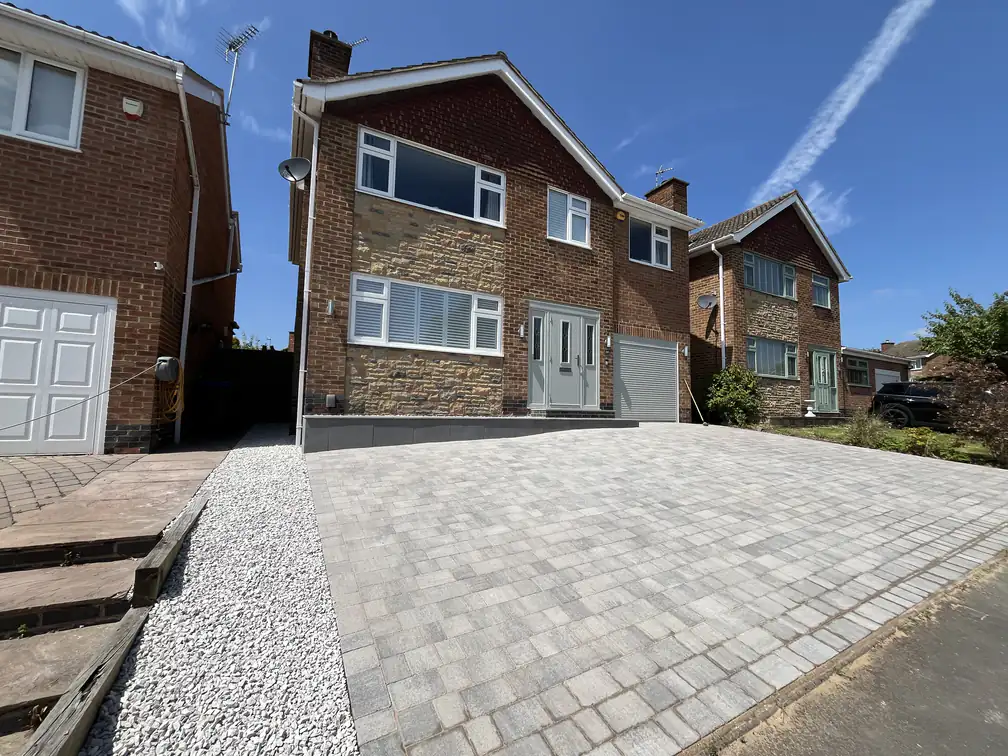 Large block paved driveway installation providing generous off-road parking for a detached home, finished with decorative gravel edging.