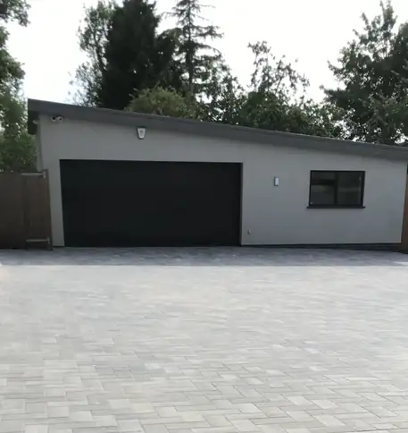 Light grey block paving forecourt serving a modern double garage, a crisp hard-wearing turning area.