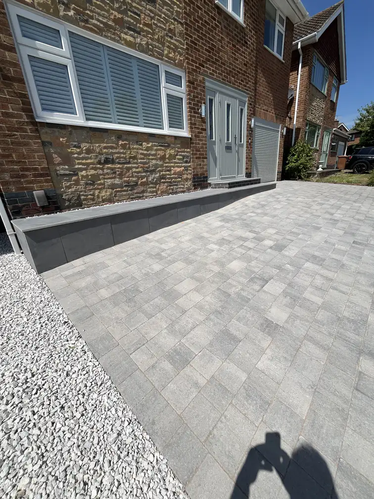 Modern grey block paving driveway edged with white decorative gravel, combining drainage with crisp styling.