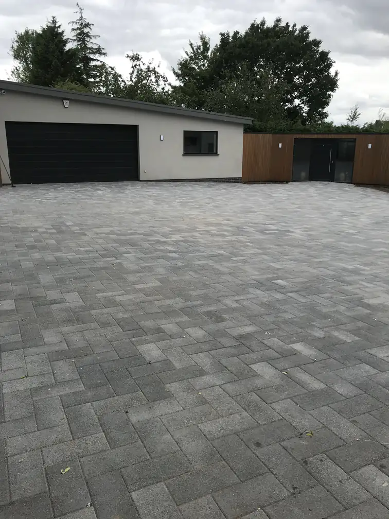 Silver-grey block paved courtyard linking house, garage and garden store for smart practical circulation space.