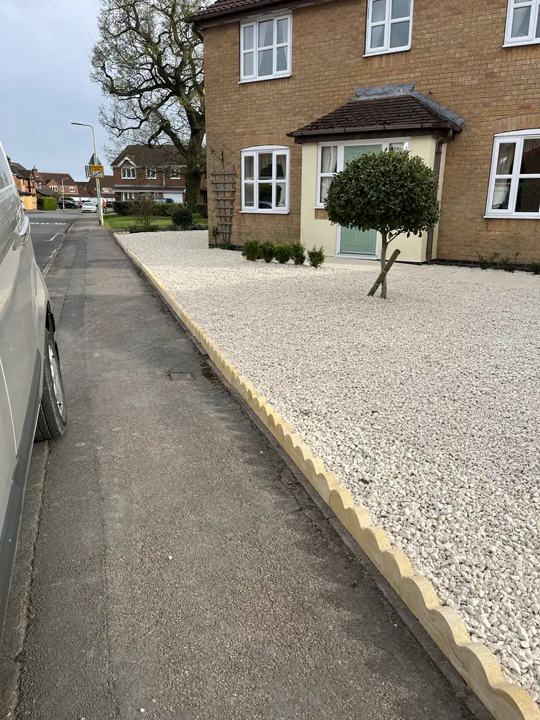 Decorative white gravel driveway with scalloped buff edging kerbs and specimen tree, a budget-friendly low-maintenance frontage.