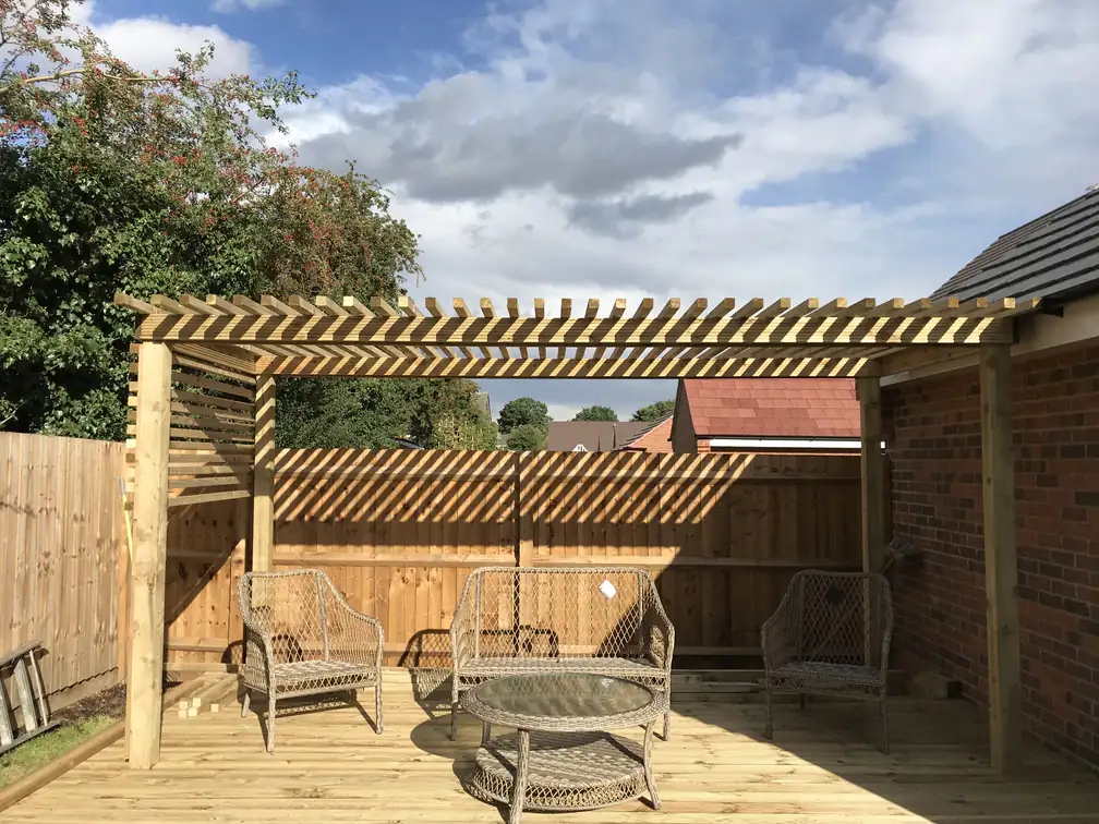 Garden pergola and raised timber decking creating a defined lounge zone in a newly fenced garden.