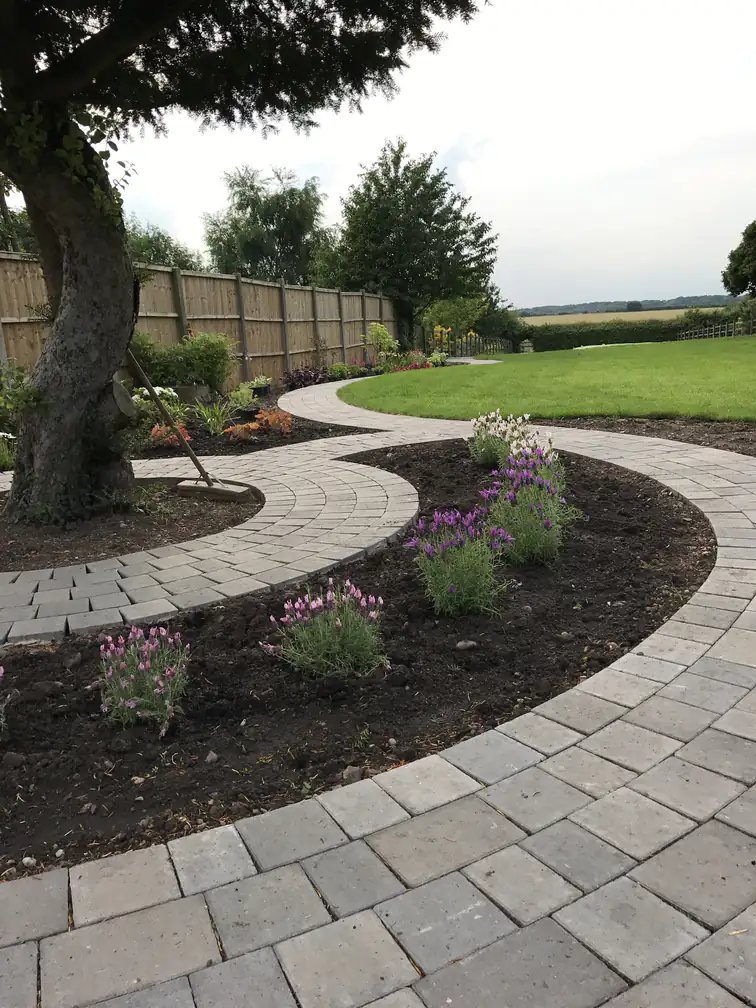 Garden landscaping with a curved block-paved path, fresh lavender planting and new lawn opening onto countryside views.