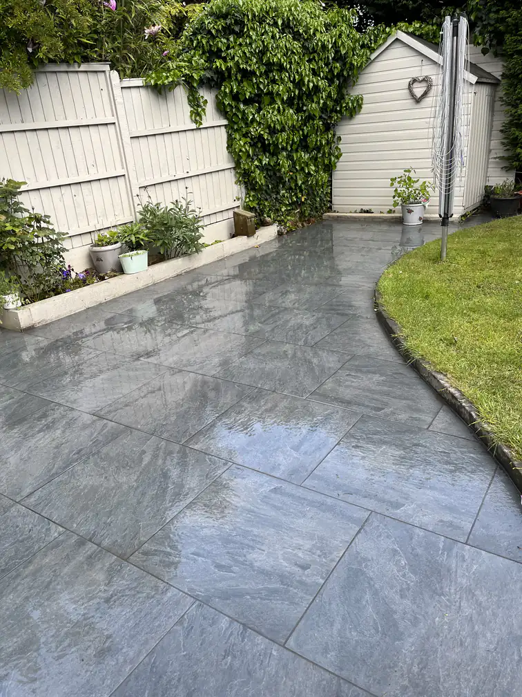 Grey porcelain path curving along a fresh lawn edge to the garden shed, smart all-weather access.