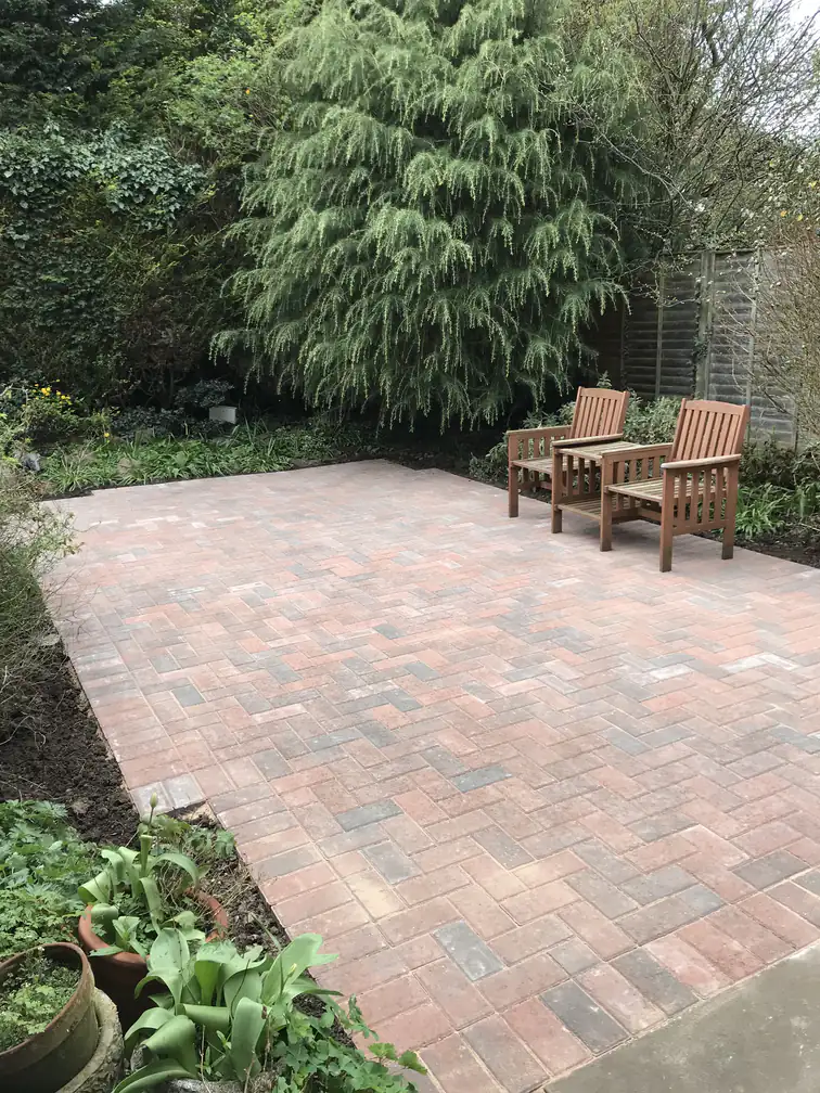 Brindle block paved patio nestled in a mature leafy garden, a warm seating corner among established planting.