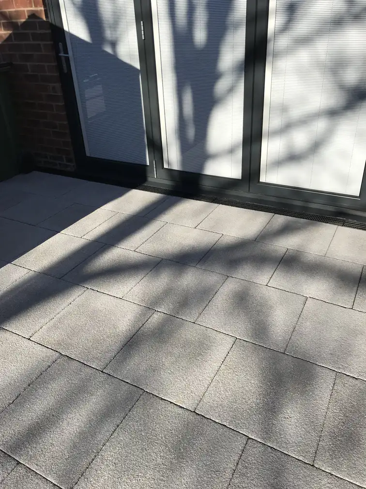Grey textured paving laid flush to anthracite bifold doors for a seamless step-out entertaining space.