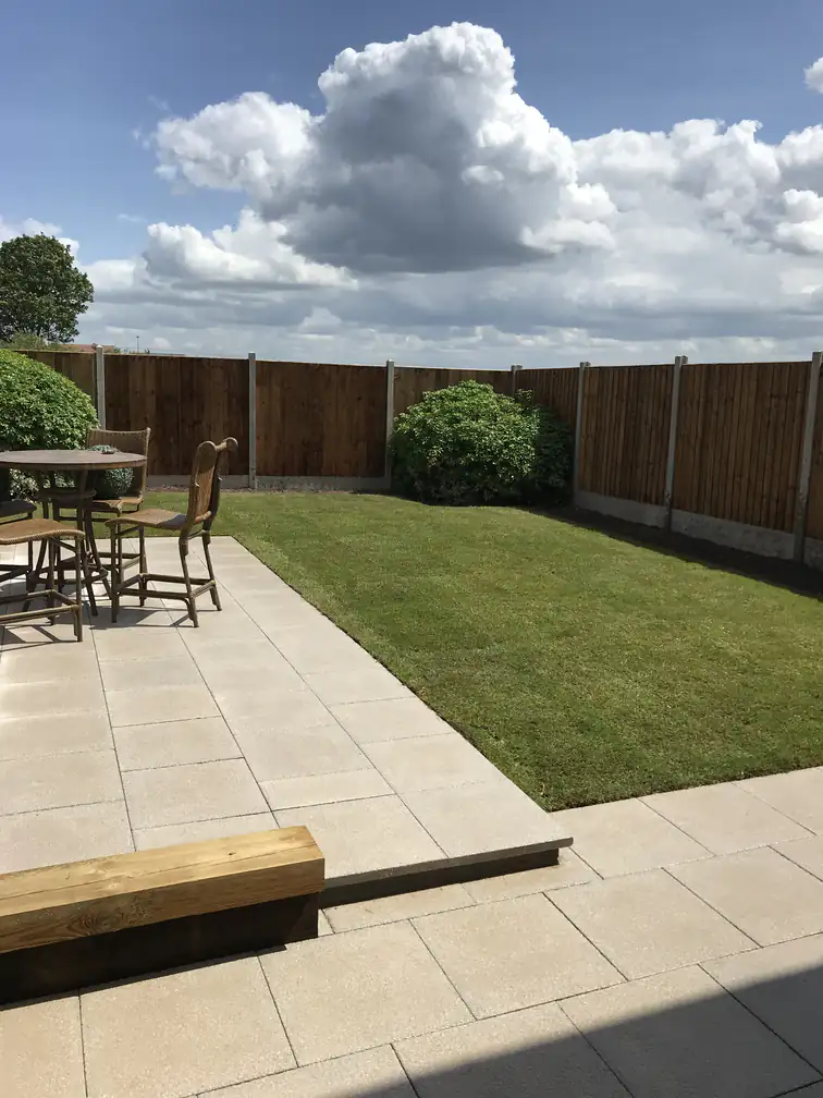 Garden makeover with ivory paved patio and newly laid lawn enclosed by timber fencing, ideal for outdoor dining.