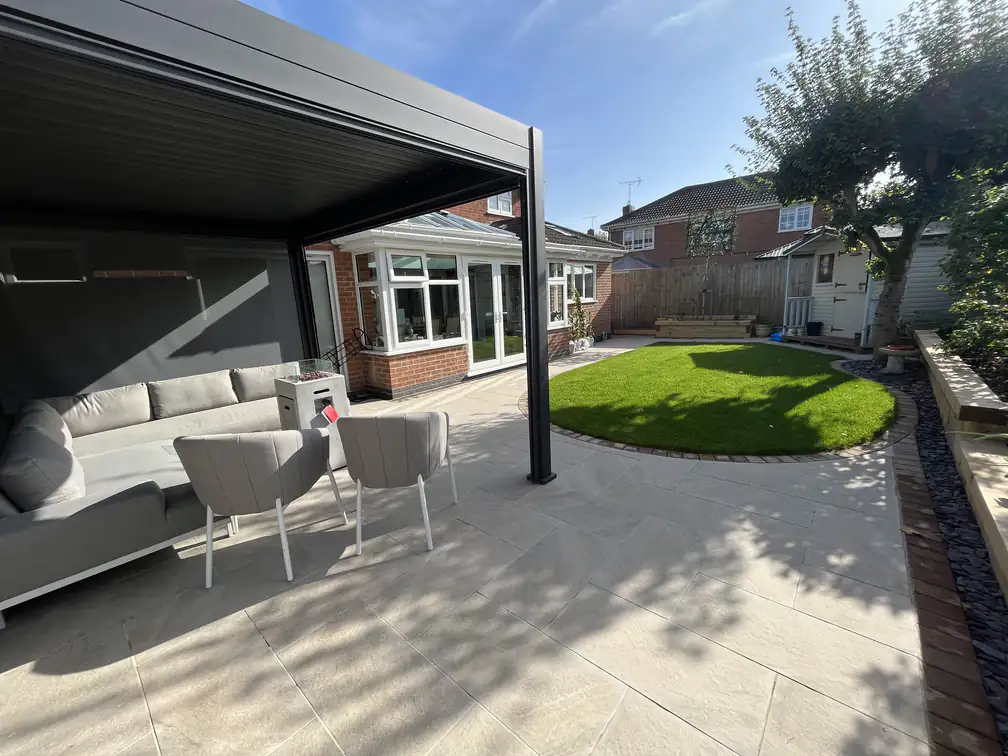 Louvred pergola over a porcelain patio with outdoor lounge furniture and artificial lawn, an all-weather entertaining space.