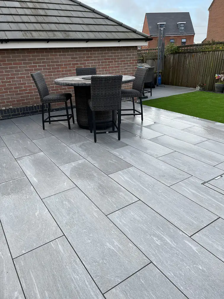 Porcelain dining patio linking the house to a brick garden room, with artificial lawn for year-round green.
