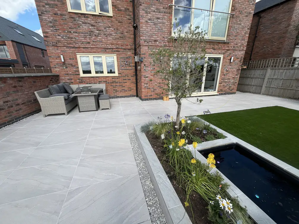 Porcelain patio with rattan corner seating beside the raised pond, an outdoor lounge made for entertaining.