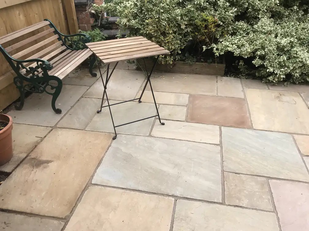 Riven Indian sandstone patio corner with garden bench and bistro table, a peaceful spot among the borders.