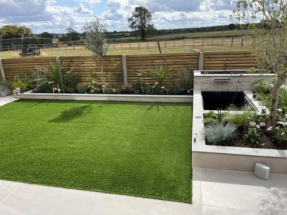 Contemporary garden with artificial lawn and porcelain-clad raised pond overlooking open paddock views, zero-mow and stylish.