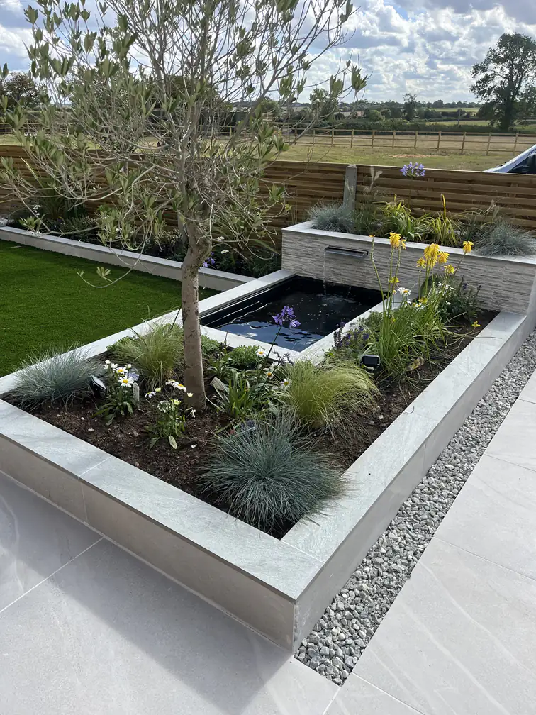 Raised pond with waterfall blade set against a countryside outlook, combining soothing water with big open skies.