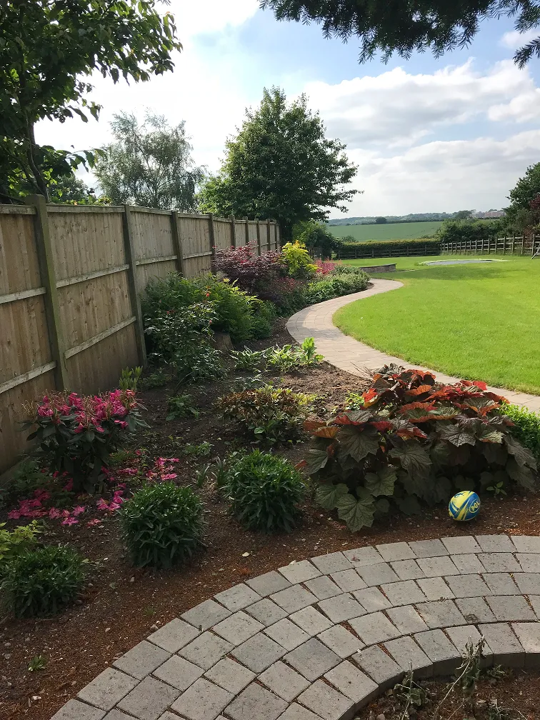 Landscaped Leicestershire garden with curved path, flower borders, lawn and timber fencing.